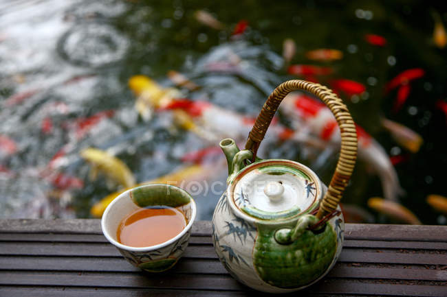 Vista de alto ângulo do conjunto de chá e peixes dourados nadando na lagoa — Fotografia de Stock