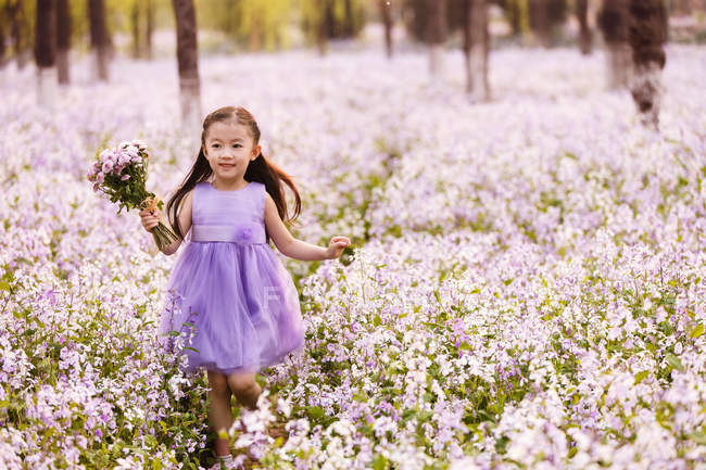 Очаровательный азиатский ребенок в платье ходить с букет цветов в поле — стоковое фото