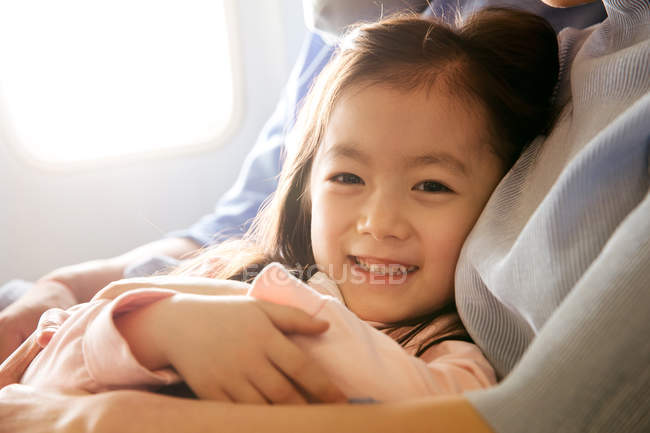 Familia feliz con un niño viajando en avión, niña sonriendo a la cámara - foto de stock