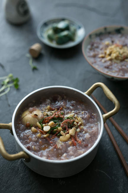 Primo piano vista di gustoso porridge di riso sano in padella sulla superficie grigia, messa a fuoco selettiva — Foto stock