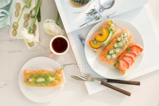 Vista superior de delicioso desayuno saludable y té en taza en mesa blanca - foto de stock