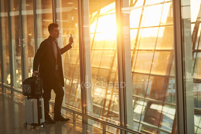 Vista lateral do jovem empresário com bagagem no aeroporto — Fotografia de Stock