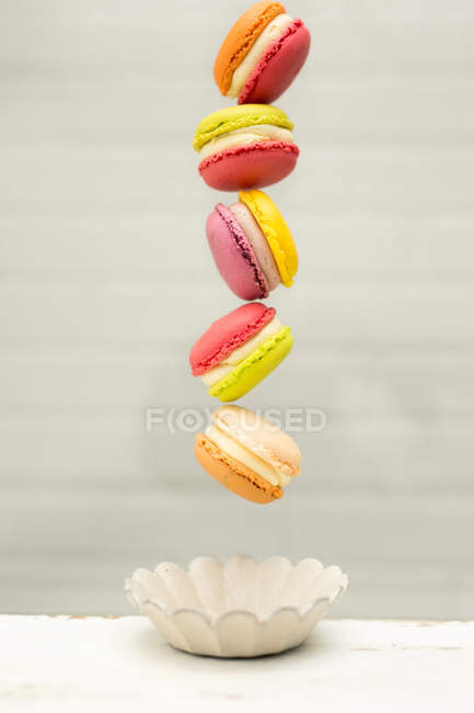 Vista da vicino di deliziosi macaron colorati dolci e ciotole su sfondo grigio — Foto stock