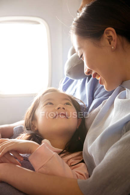 Happy family with one child traveling by plane, girl looking at mother — Stock Photo