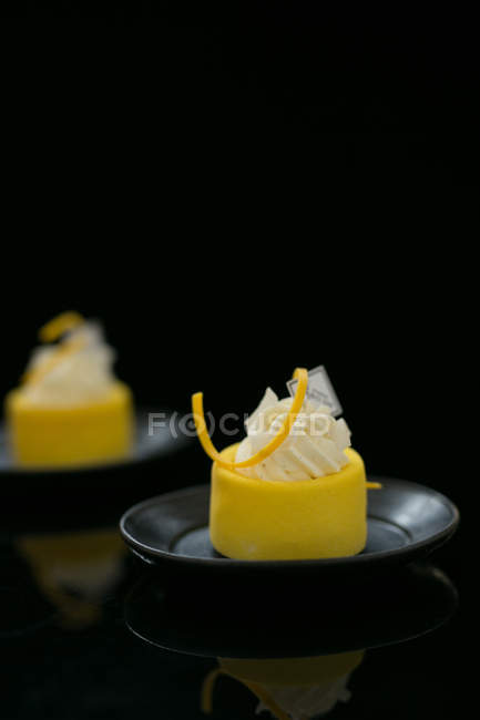 Vista de cerca de deliciosos pasteles dulces en platos negros, enfoque selectivo - foto de stock