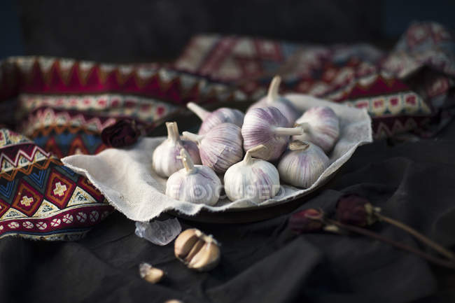 Close-up view of organic ripe garlic on tablecloth on table — Stock Photo
