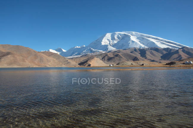 Atemberaubende Landschaft mit Karakulsee und schneebedeckten Bergen bei sonnigem Tag — Stockfoto