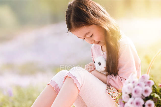 Чарівна азіатська дитина тримає милий кролик на відкритому повітрі — стокове фото