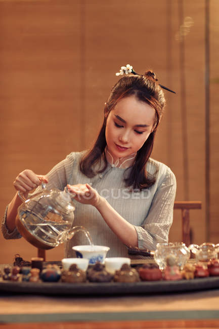 Schöne konzentrierte junge Chinesin gießt Tee — Stockfoto