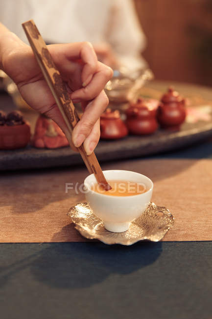 Обрезанный снимок молодой женщины, готовящей горячий органический чай в белой чашке — стоковое фото