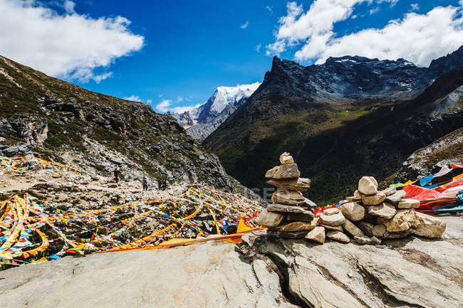 Increíble paisaje de montaña con torre de piedra, banderas de colores y montañas escénicas - foto de stock