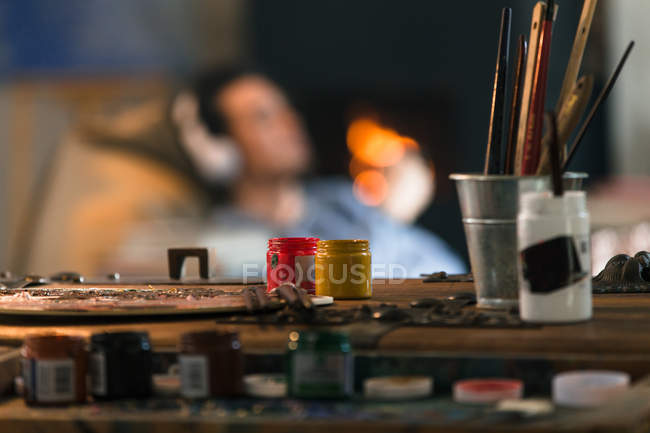 Close-up view of art tools and man in headphones resting behind, selective focus — Stock Photo