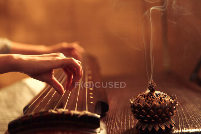 Обрезанный снимок женщины, играющей на традиционном китайском гучженском инструменте — стоковое фото