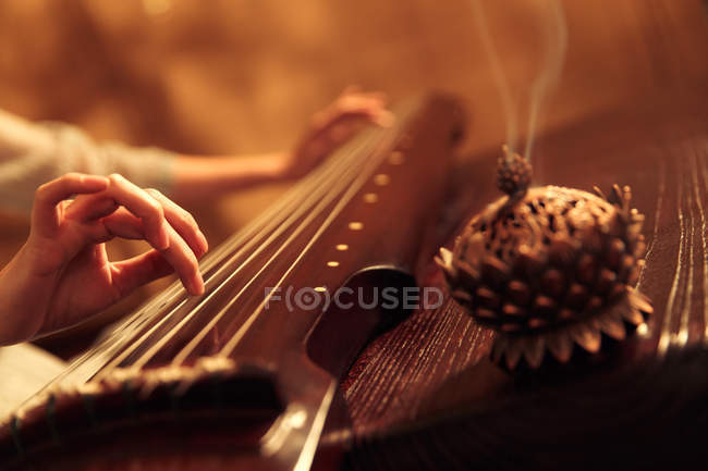 Частичный взгляд крупным планом на женщину, играющую на традиционном китайском гуженском инструменте — стоковое фото
