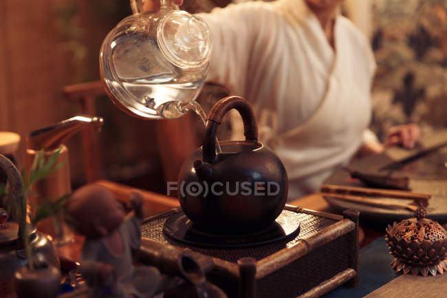 Cropped shot of young woman pouring water into teapot — Stock Photo