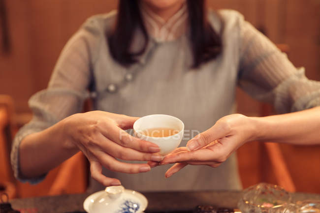 Colpo ritagliato di donna in possesso di tazza con tisana calda — Foto stock