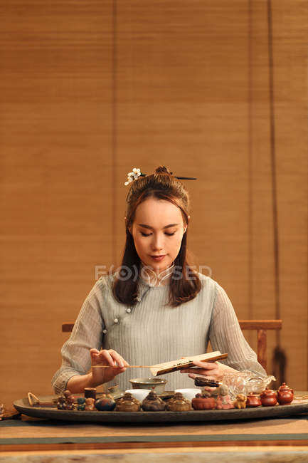 Mujer china joven en ropa tradicional haciendo té de hierbas - foto de stock
