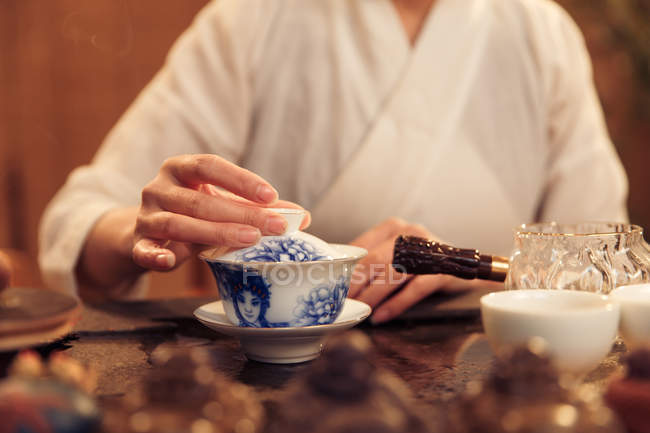 Cropped shot of woman holding porcelain container with hot beverage — Stock Photo
