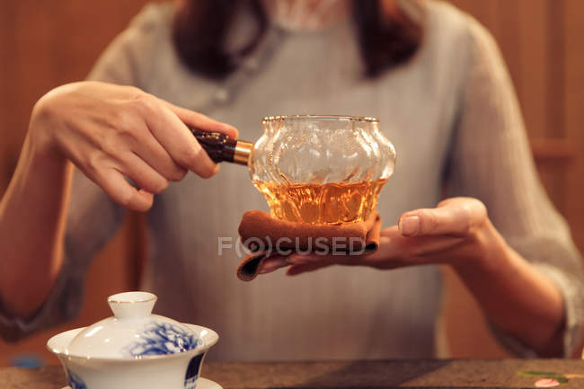 Tiro recortado de jovem segurando recipiente de vidro com chá de ervas — Fotografia de Stock