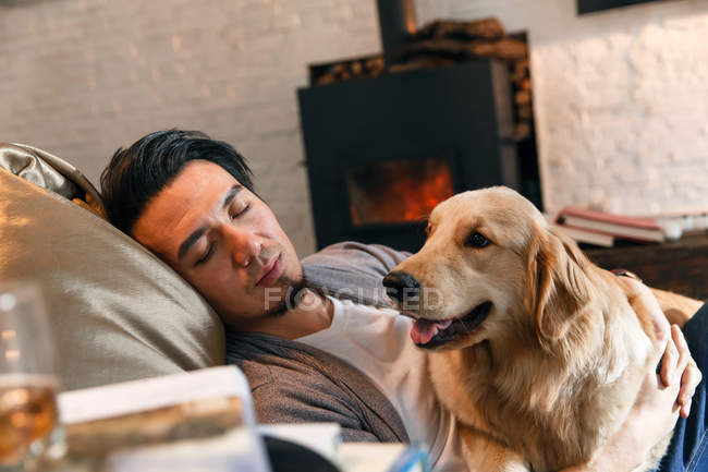 Красивий азіатський чоловік обіймає собаку і спить вдома — стокове фото
