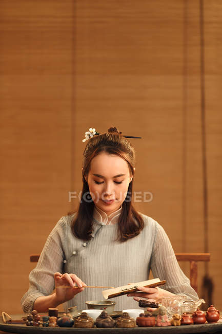 Beautiful young chinese woman in traditional clothing making herbal tea — Stock Photo