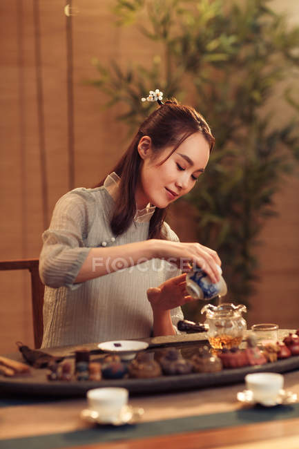 Belle souriante jeune femme chinoise verser le thé — Photo de stock