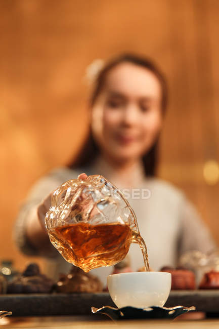 Nahaufnahme einer jungen Asiatin, die Tee in eine Tasse gießt, selektiver Fokus — Stockfoto