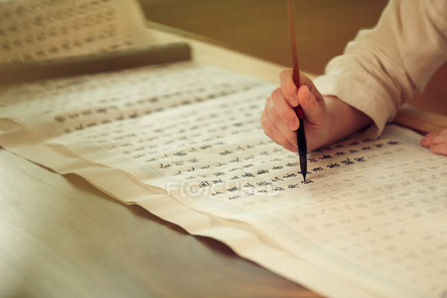 Close-up visão parcial da mulher segurando pincel caligrafia e escrever caracteres chineses — Fotografia de Stock