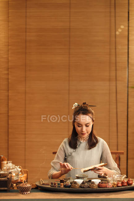 Beautiful young chinese woman in traditional clothing making herbal tea — Stock Photo