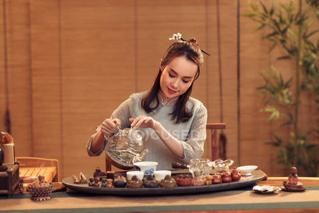 Hermosa sonriente joven china mujer verter té - foto de stock