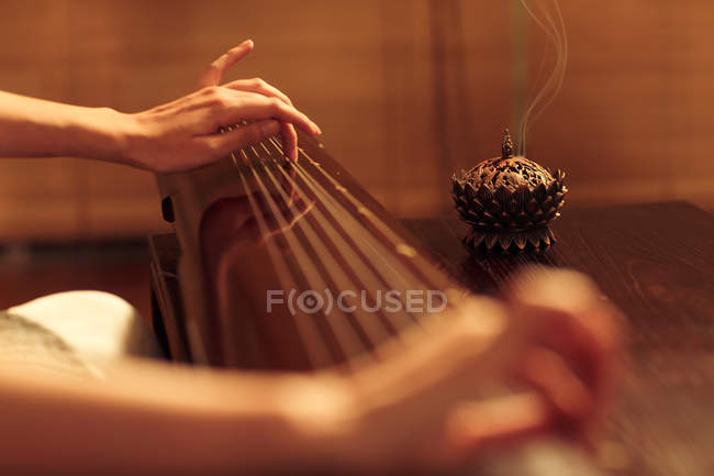 Обрезанный снимок женщины, играющей на старинном китайском струнном инструменте — стоковое фото