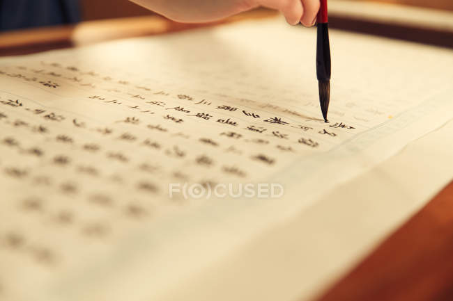 Recortado disparo de la mujer escribiendo caracteres chinos con cepillo de caligrafía - foto de stock