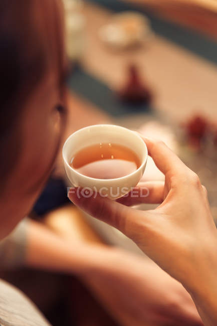 Primer plano vista de joven asiático mujer celebración taza de té - foto de stock