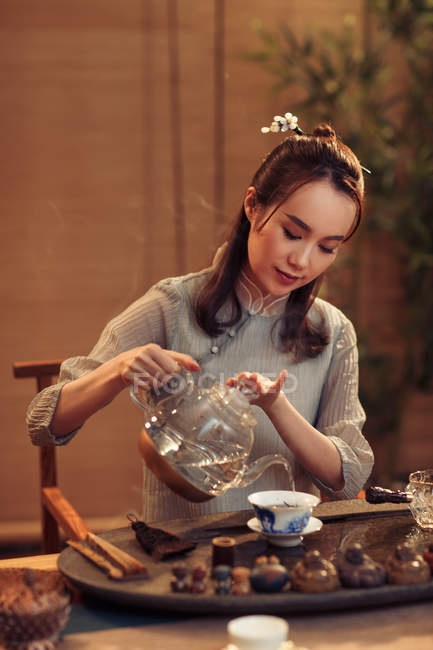 Красивая концентрированная молодая китаянка наливает чай — стоковое фото