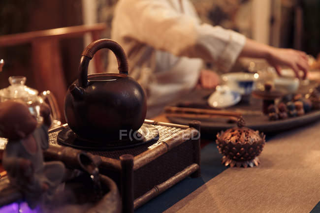 Вид крупним планом коричневий чайник і азіатська жінка сидить позаду, вибірковий фокус — стокове фото