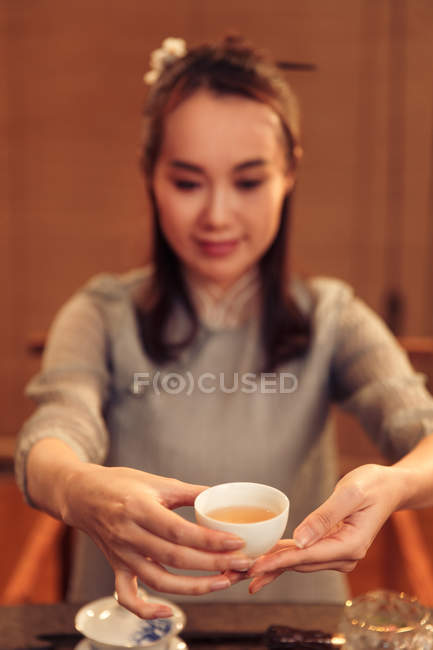 Hermosa sonriente joven asiático mujer celebración taza de té - foto de stock