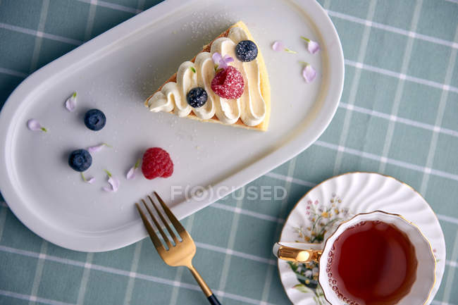 Delicious dessert with berries and cup of tea on table, top view — Stock Photo