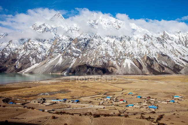 Hermosas montañas cubiertas de nieve y pueblo en el valle, Tíbet - foto de stock