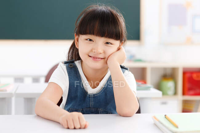 Retrato de una niña sentada en el aula - foto de stock