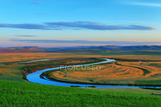Bela paisagem com grama verde, rio, colinas e céu azul — Fotografia de Stock