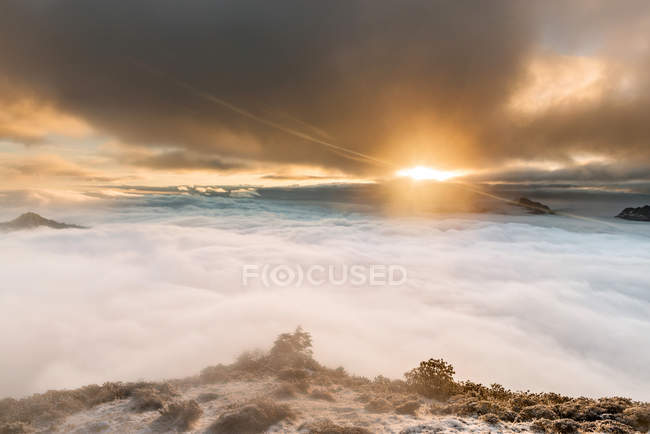 Belo pôr do sol sobre montanhas cênicas cobertas de nuvens — Fotografia de Stock