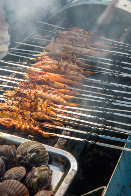 Close-up view of grilled shrimps on skewers preparing on grill — Stock Photo