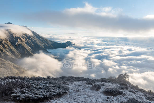 Paisaje de montaña con montañas cubiertas de nieve en las nubes - foto de stock