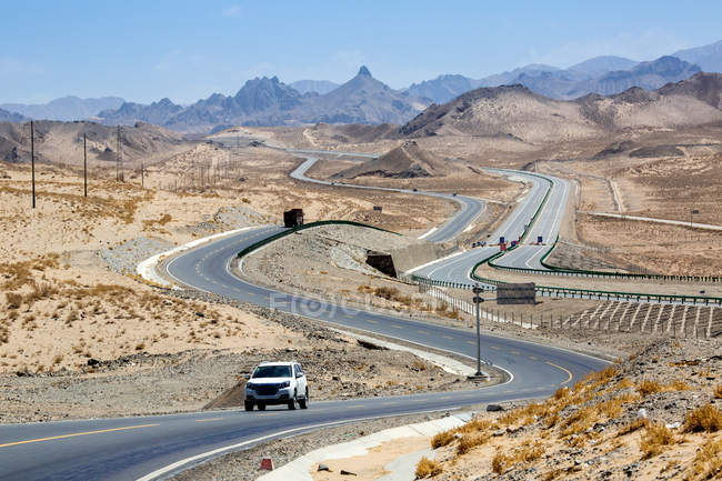 Véhicules à moteur sur l'autoroute Qinghai-Tibet et les montagnes pendant la journée — Photo de stock