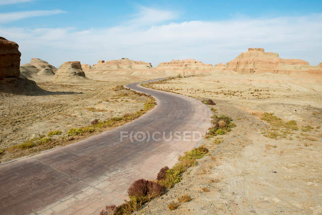 Strada asfaltata nel deserto con montagne rocciose panoramiche nella giornata di sole — Foto stock