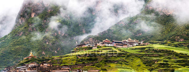 Hermoso paisaje con edificios en la pendiente de la montaña, Gannan, Gansu, China - foto de stock