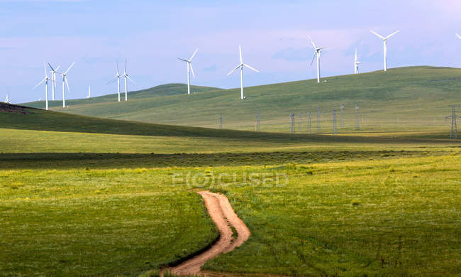 Pathway and windmills on green hills at sunny day — Stock Photo