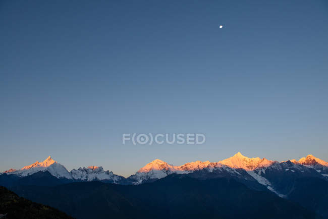 Incrível paisagem montanhosa com montanhas cobertas de neve durante o nascer do sol — Fotografia de Stock