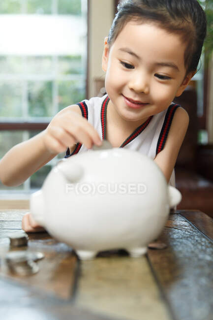Menina soltando moeda na caixa de poupança — Fotografia de Stock