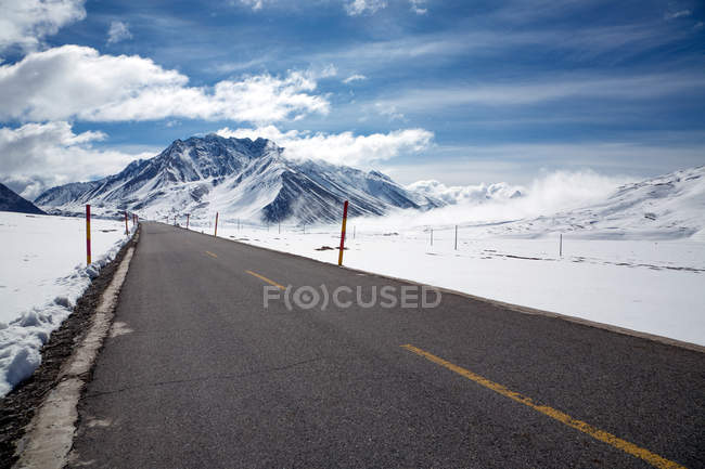 Estrada de asfalto vazia e belas montanhas cobertas de neve no Tibete — Fotografia de Stock